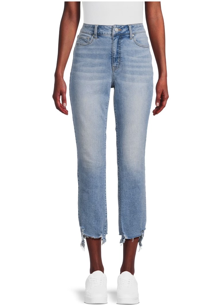 Plus-size woman wearing high-rise medium wash skinny jeans with tan mule heels, front view on white background